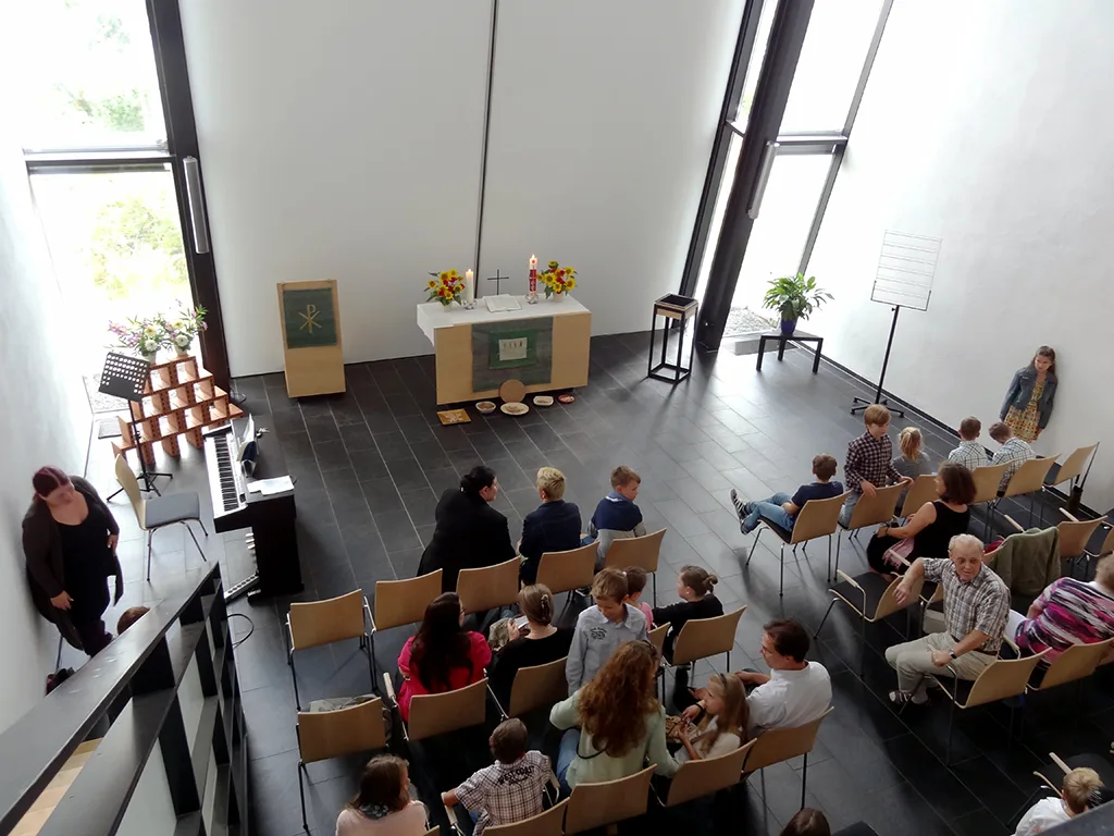 Blick von der Empore in die Kirche, Familien sitzen in den Bankreihen.